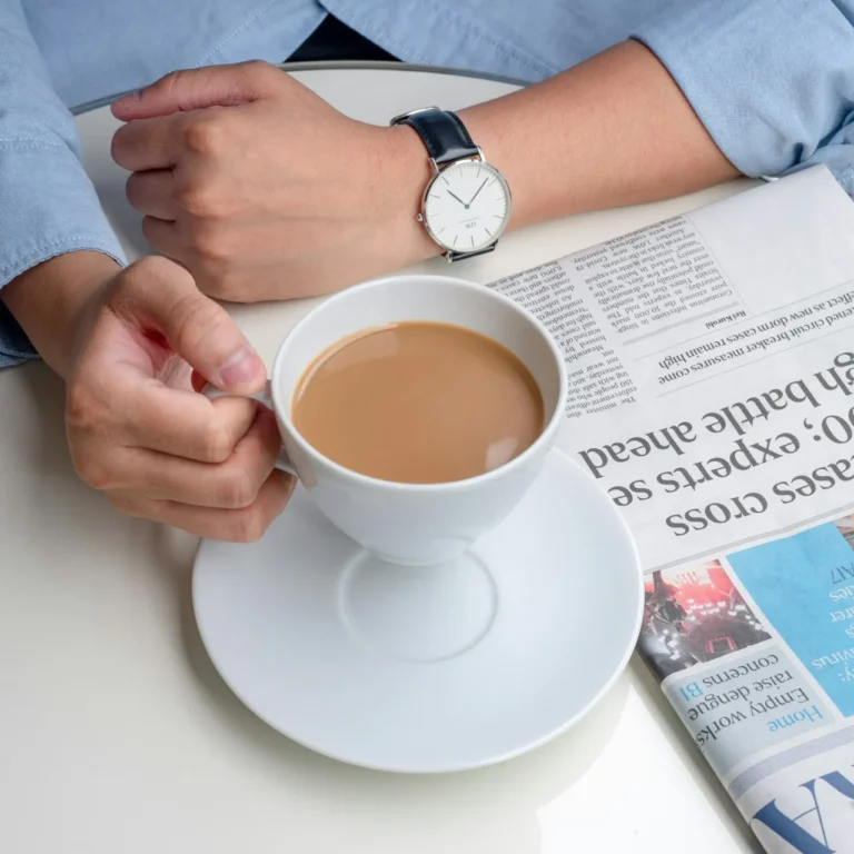 Persona lee el periódico con un café